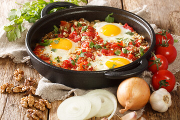 Adjarian breakfast Chirbuli of fried eggs with tomatoes, onions and walnuts close-up in a frying pan on the table. horizontal