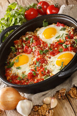 Ajarian Chirbuli is a dish from Georgia Ajara region made with eggs, tomatoes, onion and walnuts, it is a popular breakfast meal closeup in the pan. Vertical