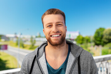 fitness, sport and people concept - portrait of happy smiling young man outdoors