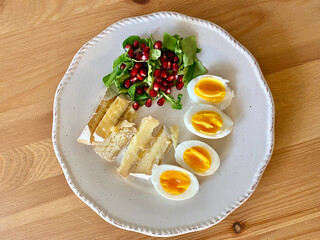 Healthy Homemade Breakfast Plate with Moldy Cheese, Boiled Eggs, Rucola Arugula or Rocket Leaves with Pomegranate Seeds on Wooden Table.