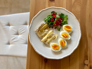 Healthy Homemade Breakfast Plate with Moldy Cheese, Boiled Eggs, Rucola Arugula or Rocket Leaves with Pomegranate Seeds on Wooden Table.
