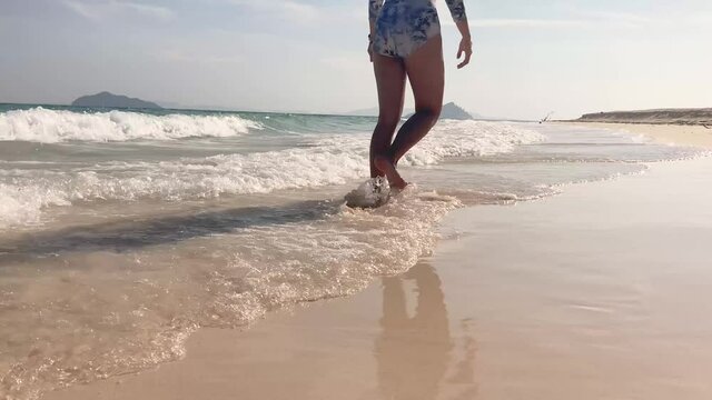 legs walking on sandy beach in morning sunlight. waves lapping on sandy beaches, slow motion scenic view, lifestyle young female in swinging suit relaxing on summer holiday vacation in BuLon island