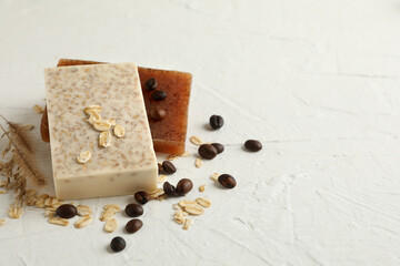 Natural soap, oat and coffee seeds on white table