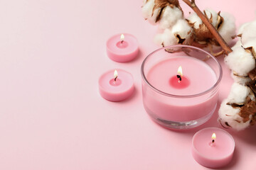 Scented candles and cotton on pink background