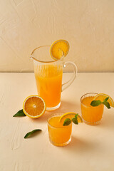 drink, detox and diet concept - glasses with fruit orange juice and peppermint on table