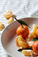 food, healthy eating and fruits concept - close up of mandarins on plate over drapery