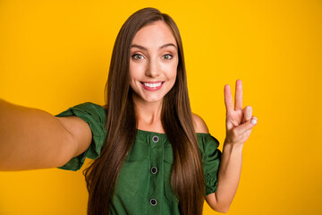Self-portrait of pretty cheerful long-haired girl blogger showing v-sign having fun isolated over...