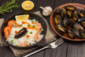 Shrimps and mussels with rice in frying pan. Mussels on plate