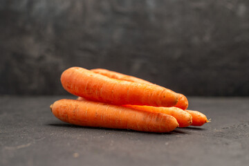 Front close view of organic fresh carrots on dark background