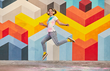 Excited young woman jumping against geometric wall