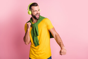Photo of happy man dance look empty space wear earphones jumper on shoulders isolated on pink color...