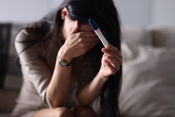 Sad woman holding pregnancy test in her hand