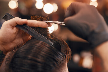 Crop hairstylist cutting hair of client in barbershop