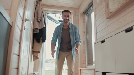 Handheld low angle shot of happy father standing by front door in house and hugging his cute daughter after returning home