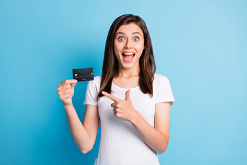 Photo of young happy crazy excited smiling positive girl pointing finger at credit card isolated on blue color background