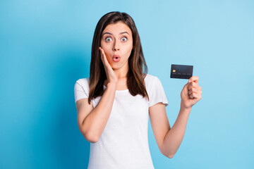 Photo of young shocked amazed surprised girl hold hand cheek showing credit card isolated on blue color background