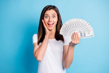 Photo of young shocked happy smiling amazed lovely girl with money hold hand cheek isolated on blue...
