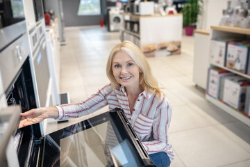Blonde customer choosing oven in a showroom and smiling