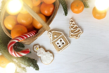 gingerbread snowman, house and tree on the table with a basket of tangerines, fir branches and lights of garlands. festive delicious decorations