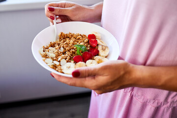 Woman eating healthy breakfast bowl, hold in hand