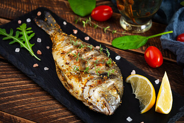 Grilled dorado fish on wooden background. Roasted seafish with spice and herbs