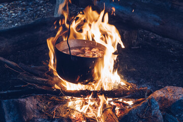 Tourist cauldron on fire. Food cooking in camping pot. Soup or chowder outdoors meal. Wildlife...