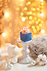 Fototapeta na wymiar Mini mousse pastry dessert with blue velour. garland lamps bokeh background. In the form of gift box, ribbons of chocolate. Modern european cake. French cuisine. Christmas theme