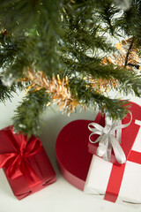 Presents wrapped in red and white paper under decorated Christmas tree, selective focus