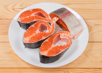 Pieces of uncooked rainbow trout on dish on rustic table