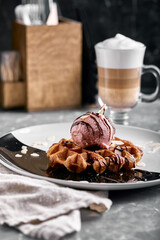 Viennese waffles with ice cream, chocolate and latte. Close-up. On the plate