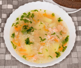 Bowl of clear trout soup on a table, top view