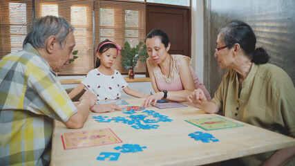 Asian Family have funny happy time playing board game together in living room at apartment