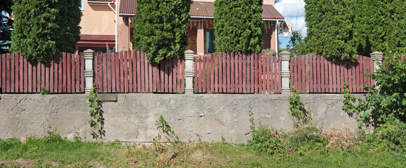 High rustic fence made of concrete and wood