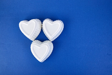 Fototapeta premium White ceramic hearts on blue trend color background.
