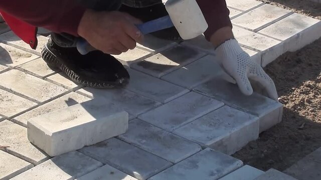 a worker lays paving slabs on the street	