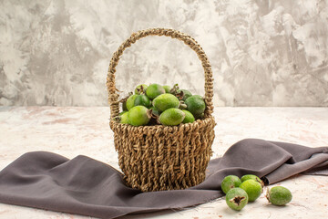 Top view of fresh feijoa a small green vitamin bomb in a basket on black towel on white background