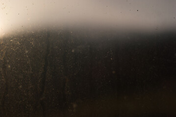 Dirty environment concept. Abstract image of a mountain seen from behind a dirty window at dusk. 