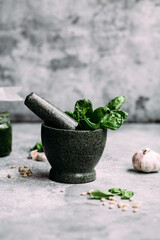 Cooking pesto sauce in stone mortar on gray background