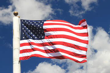 US american flag waving in front of blue sky with clouds