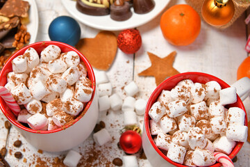sweet food top view background for merry christmas or new year holiday decoration - chocolate candies, tangerines, cookies, marshmallow and cocoa latte on white wood