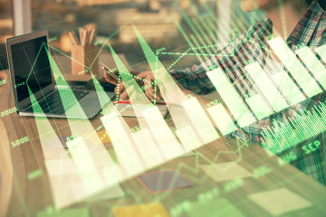 Double exposure of businesswoman hands typing on computer and forex graph hologram drawing....