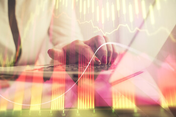 Double exposure of businesswoman hands typing on computer and financial graph hologram drawing. Stock market analysis concept.