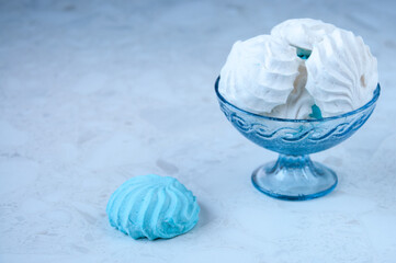 Marshmallows white and blue in a glass vase on the table, space for text