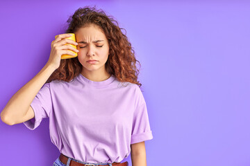 unhappy sleepy girl with cup of tea isolated in studio with purple background, want to sleep in the morning before studying