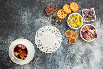 top shot of white lace and bowls of dry flowers and chocolate bars with herbal tea on grey ground