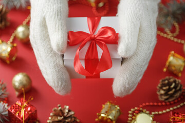 White gift box with a red bow in the mittens. Christmas or new year gift.