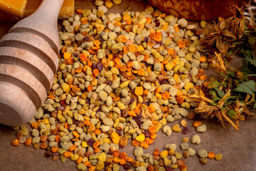 Close up bee pollen, bee wax, dried flowers and honey in the background