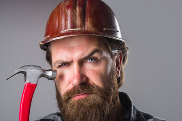 Worker with hammer. Bearded man with hammer in hands. Bearded worker. Close up portrait of man with...