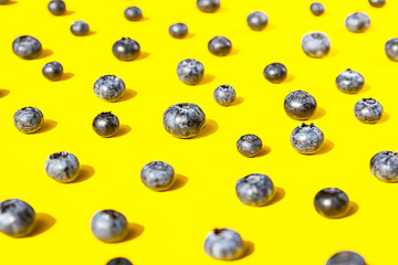 Creative pattern made of blueberries on yellow background. Berries minimal concept.