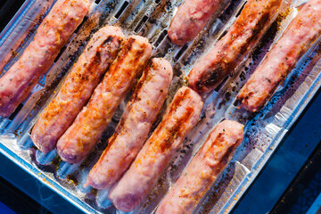 Sausages meat grilling on gas grill